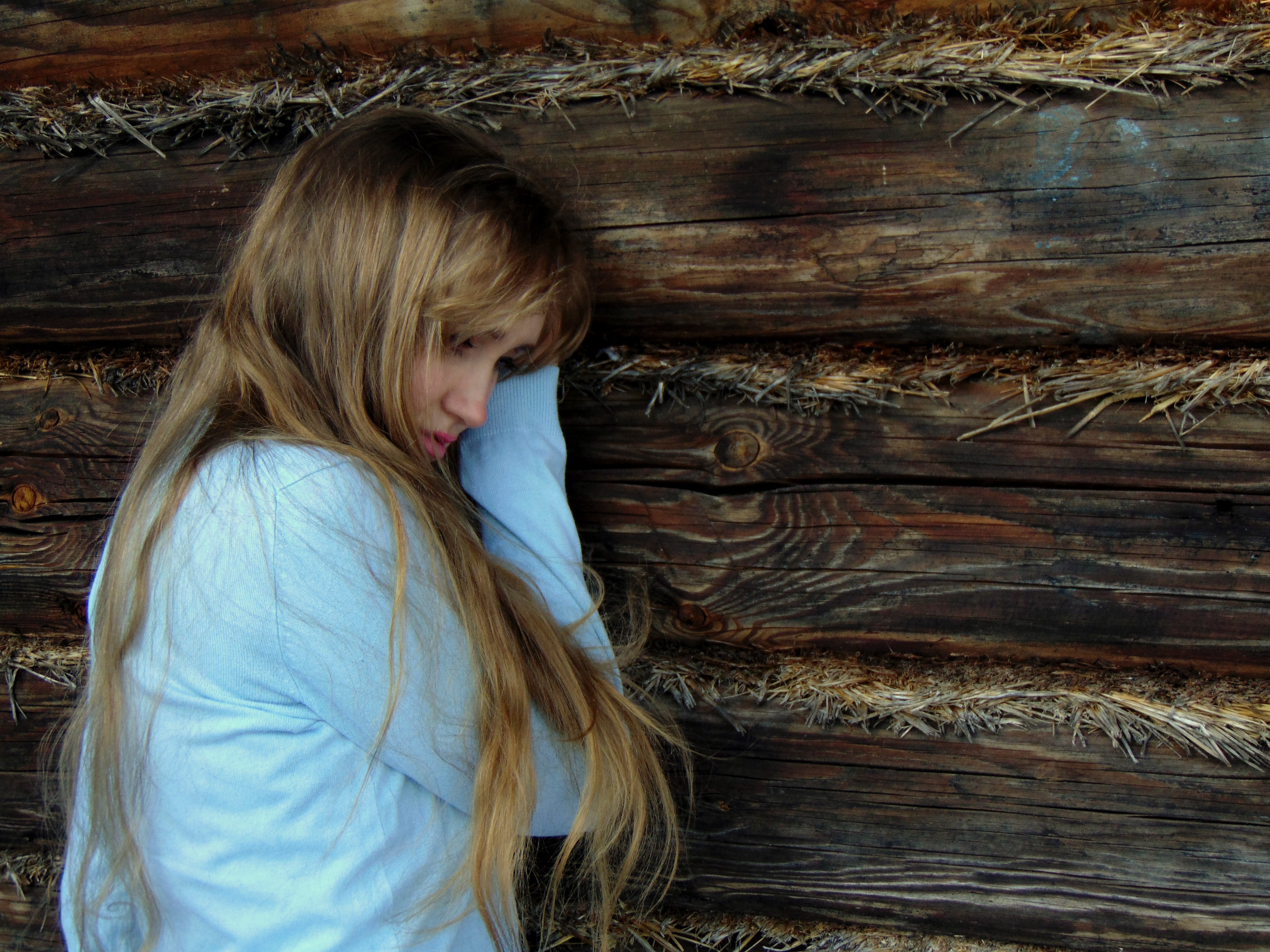 mulher encostada na parede de madeira preta
